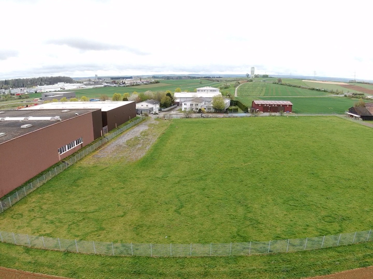 Landwirtschaftliche Hofanlage mit Weidefläche, Scheune und Industriegebäuden in ländlicher Umgebung.